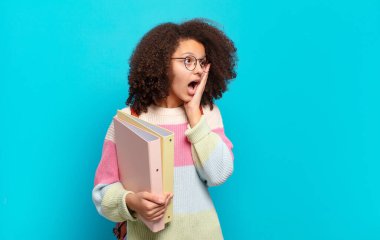 Oldukça afro bir genç mutlu, heyecanlı ve şaşırmış hissediyor, iki eli yüzü üzerinde yana bakıyor. öğrenci konsepti