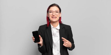 Genç ve çekici kızıl saçlı kadın heyecanlı ve şaşırmış görünüyor. Kenarlarını ve yukarısını göstererek mekanı kopyalamaya çalışıyor. iş kavramı