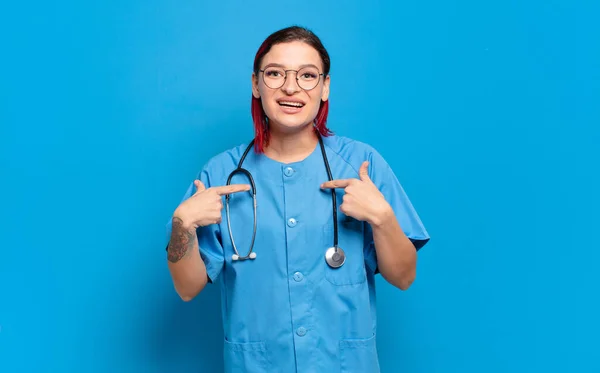 若い魅力的な赤い髪の女性の幸せ 驚きと誇りを感じ 興奮して 驚いて見て自分自身を指しています 病院看護師のコンセプト — ストック写真
