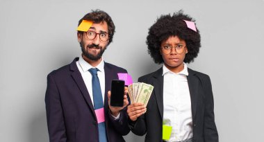 Genç iş adamları şaşkın ve şaşkın görünüyor, gergin bir jestle dudaklarını ısırıyorlar, sorunun cevabını bilmiyorlar. mizahi iş konsepti