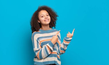 Mutlu bir şekilde gülümseyen ve iki elini de kopyalama boşluğunda gösteren bir kız.