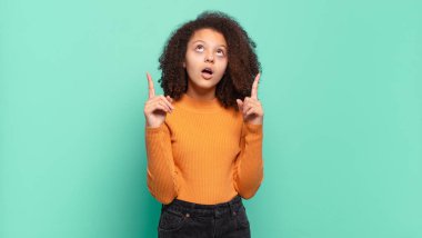 Korkmuş ve ağzı açık hisseden kız şaşırmış ve şaşırmış bir bakışla yukarıya bakıyor.