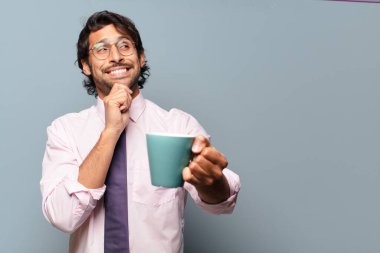 Elinde kahve fincanı olan yakışıklı Hintli bir iş adamı.