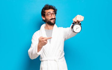 Bornoz ve çalar saat takan genç sakallı adam.