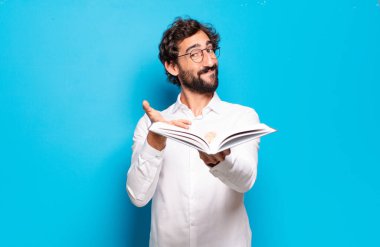 Mavi arkaplan üzerine kitabı olan genç sakallı adam.
