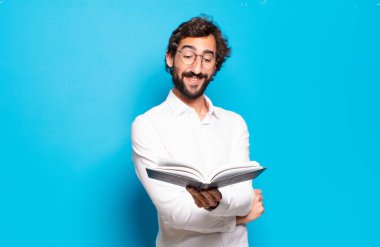 Mavi arkaplan üzerine kitabı olan genç sakallı adam.