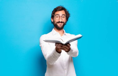 Mavi arkaplan üzerine kitabı olan genç sakallı adam.