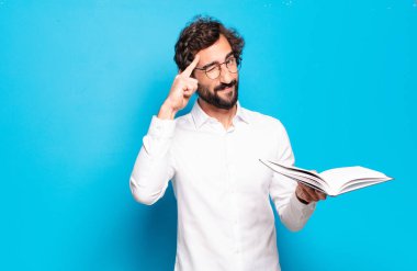 Mavi arkaplan üzerine kitabı olan genç sakallı adam.