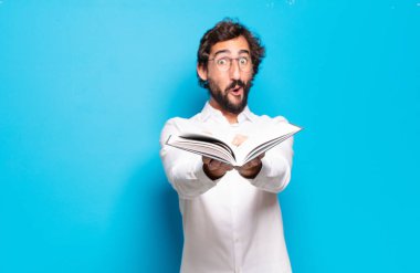 Mavi arkaplan üzerine kitabı olan genç sakallı adam.