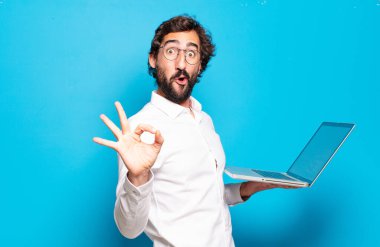 Genç sakallı adam dizüstü bilgisayar tutuyor.