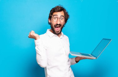 Genç sakallı adam dizüstü bilgisayar tutuyor.