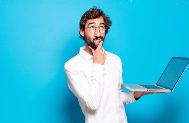 Genç sakallı adam dizüstü bilgisayar tutuyor.