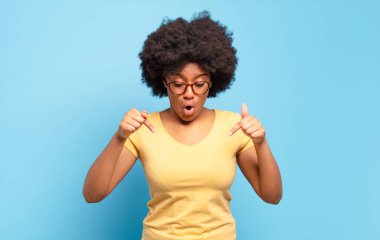  Şok olmuş, ağzı açık ve şaşkın, inançsızlık ve şaşkınlık içinde bakıyor ve aşağı doğru işaret ediyor.