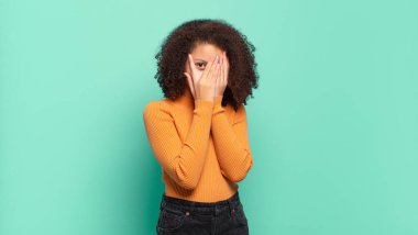  Korkuyor ya da utanıyor, dikizliyor ya da ellerle yarı kapalı gözlerle gözetliyor.