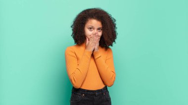  Mutlu ve heyecanlı, şaşırmış ve şaşkın ellerle ağzını kapatmış, tatlı bir ifadeyle kıkırdıyor.