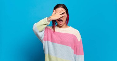  Şok olmuş, korkmuş ya da korkmuş görünüyor, yüzleri elle kaplıyor ve parmaklarının arasına bakıyor.