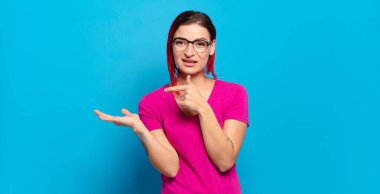  Gülümsüyor ve bir objeyi göstererek veya reklamını yaparak avucunun içindeki kopyalama alanını işaret ediyor.