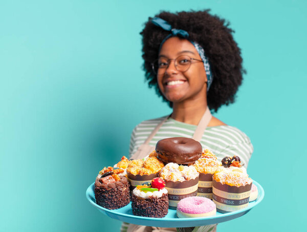 young pretty afro woman baker with cakes