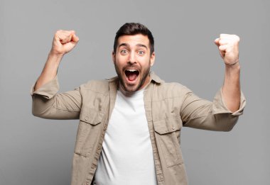 Yakışıklı sarışın adam zafer çığlıkları atıyor. Heyecanlı, mutlu ve şaşırmış görünüyor. Kutlama yapıyor.