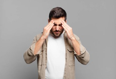 Yakışıklı, sarışın, stresli ve hayal kırıklığına uğramış bir adam. Baskı altında çalışıyor, başı ağrıyor ve sorunları var.