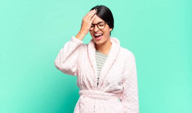 Genç ve güzel bir kadın gülüyor ve alnına şaplak atıyor. Unuttum ya da aptalca bir hataydı. pijama konsepti 