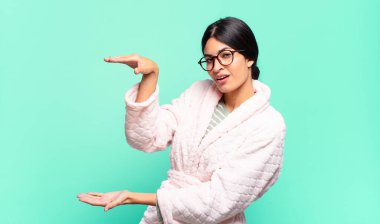 Genç ve güzel bir kadın bir objeyi iki eliyle fotokopi alanında tutuyor, bir objeyi gösteriyor, sunuyor ya da reklamını yapıyor. pijama konsepti