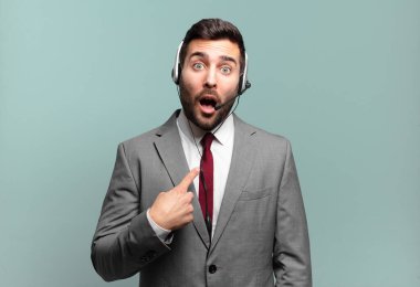 Genç işadamı ağzı açık bir şekilde kendi kendine pazarlama kavramına işaret ederek şok olmuş ve şaşırmış görünüyor.