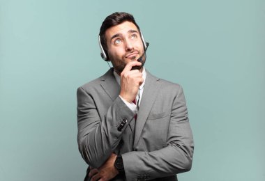 Genç işadamı düşünüyor, kuşkulu ve şaşkın hissediyor, farklı seçeneklerle, tele pazarlama kavramını hangi kararda kullanacağını merak ediyor.