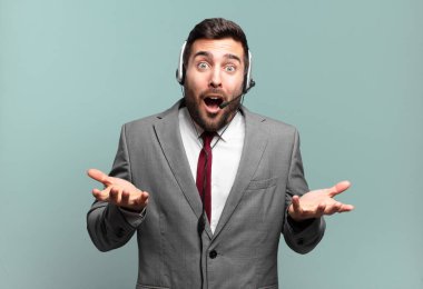 Genç işadamı şok olmuş, şaşırmış, endişeli ve paniklemiş hissediyor. Stresli ve dehşete düşmüş bir şekilde tele pazarlama konseptiyle bakıyor.