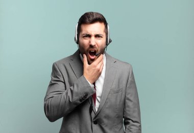 Ağzı ve gözleri açık, eli çenesinde genç bir işadamı, nahoş bir şekilde şokta, ne diyor ya da vay be tele pazarlama konsepti