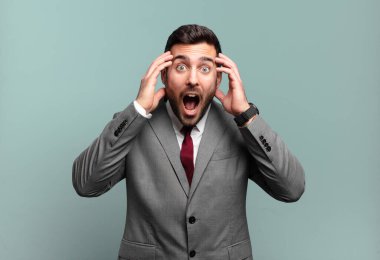 Genç, yakışıklı iş adamı, el ele tutuşuyor, ağzı açık, son derece şanslı, şaşırmış, heyecanlı ve mutlu hissediyor.