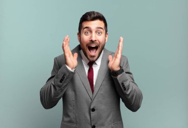 Genç ve yakışıklı iş adamı, beklenmedik bir sürprizden dolayı şaşkın ve heyecanlı, güler yüzlü, şaşkın ve mutlu hissediyor.