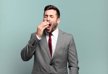 Genç ve yakışıklı iş adamı tembelce esniyor. Sabahın köründe uykulu, yorgun ve sıkkın görünüyor.