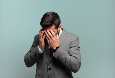 Genç ve yakışıklı iş adamı üzgün, hayal kırıklığına uğramış bir bakışla gözlerini kapatıyor. Ağlıyor, yan gözle bakıyor.