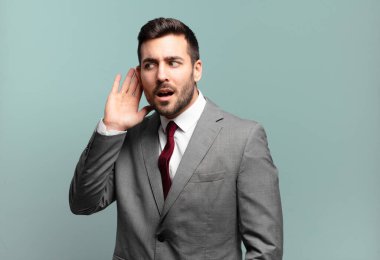 Genç ve yakışıklı iş adamı ciddi ve meraklı görünüyor, dinliyor, gizli bir konuşma veya dedikodu duymaya çalışıyor, kulak misafiri oluyor.