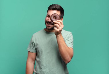 Çikolatalı donutu olan genç, sarışın bir adam. kahvaltı kavramı