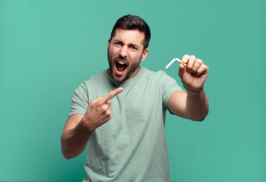 Elinde sigara tutan genç yakışıklı bir adam. sigara içmeyi bırak