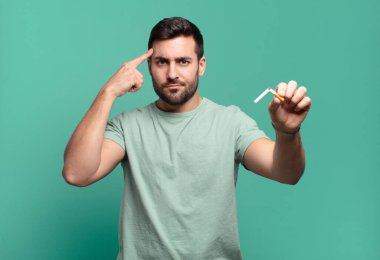 Elinde sigara tutan genç yakışıklı bir adam. sigara içmeyi bırak