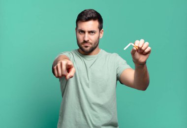 Elinde sigara tutan genç yakışıklı bir adam. sigara içmeyi bırak