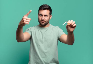 Elinde sigara tutan genç yakışıklı bir adam. sigara içmeyi bırak