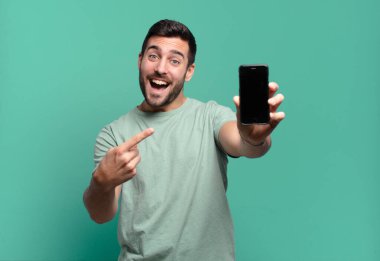 Genç yakışıklı adam cep telefonunu kullanıyor.