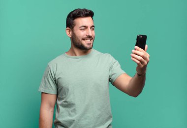 Genç yakışıklı adam cep telefonunu kullanıyor.