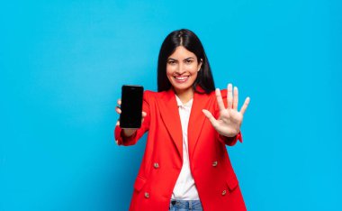 Genç İspanyol kadın gülümsüyor ve arkadaş canlısı görünüyor. 5 ya da 5 numarayı gösteriyor. Eli önde, geriye doğru sayıyor. telefon ekran kopyalama alanı