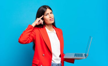 Genç İspanyol kadın şaşkın ve şaşkın hissediyor. Deli, deli ya da aklını kaçırmış olduğunu gösteriyor. dizüstü bilgisayar