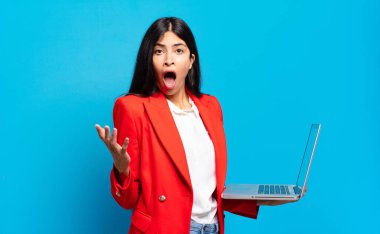 Genç İspanyol kadın ağzı açık ve şaşırmış, şok olmuş ve inanılmaz bir sürprizle şaşkına dönmüş. dizüstü bilgisayar