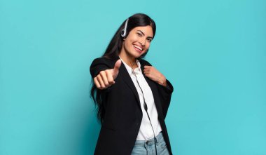 Genç İspanyol tele pazarlamacı kadın gururlu, kaygısız, kendinden emin ve mutlu başparmaklarıyla gülümsüyor.