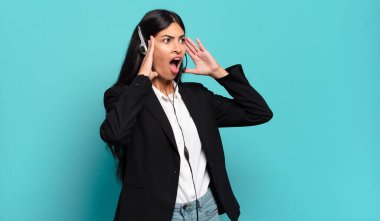 Genç İspanyol pazarlamacı kadın kendini mutlu, heyecanlı ve şaşırmış hissediyor. İki eli yüzü de havada bir tarafa bakıyor.