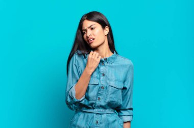 Genç Latin asıllı sıradan bir kadın stresli, endişeli, yorgun ve hayal kırıklığına uğramış, gömleğini çekiştirmiş, sorunlardan bıkmış gibi görünüyor.