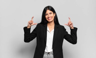 Genç İspanyol iş kadını çerçeveletiyor ya da iki eliyle kendi gülüşünü özetliyor, olumlu ve mutlu görünüyor, sağIık kavramı