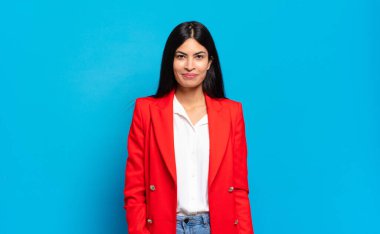 Genç İspanyol iş kadını pozitif ve kendinden emin gülümsüyor. Tatmin olmuş, arkadaş canlısı ve mutlu görünüyor.